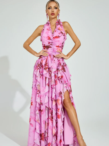 Model in pink floral halter-neck maxi dress with cascading ruffles and high-slit skirt.