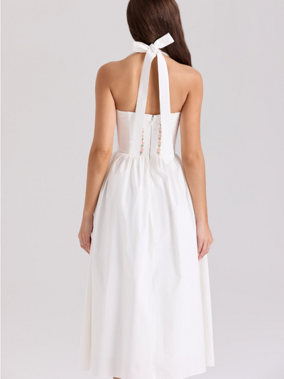 Back view of white midi dress with corset bodice and halter tie bow; pink floral embroidery on back panels.