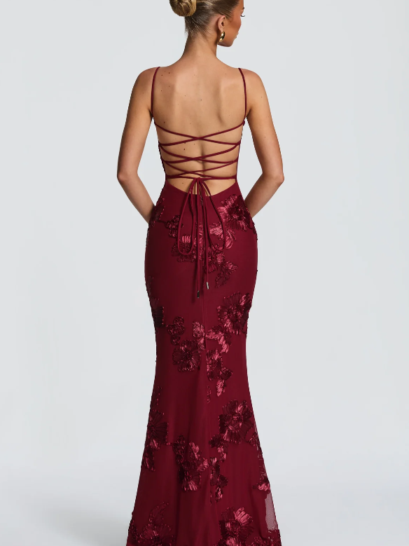 Back view of burgundy floral jacquard mermaid maxi dress with lace-up corset back and thin spaghetti straps.