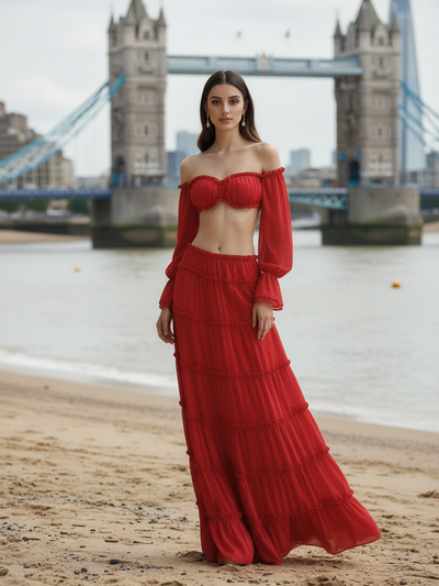 Scarlet ruffle off-shoulder tiered maxi set displayed on model at the beach with Tower Bridge in background.