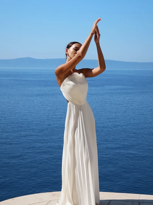 Exclusives High Slit Strapless Shell Pleated Backless Gown Maxi Dress in white worn by model by the sea