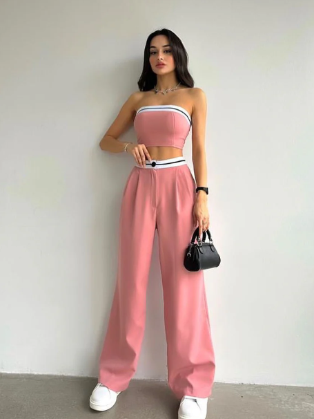 Model in pink strapless tube top with white/black trim and matching pink wide-leg pants, white sneakers, black handbag.