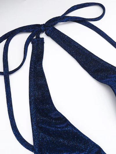 Deep navy blue glitter fabric with slender halter neck straps tied in a knot, close-up of a backless halter-neck design.