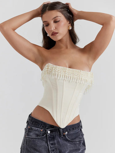 Off-white beaded fringe strapless corset top with pearl fringe and structured boning, paired with dark jeans.