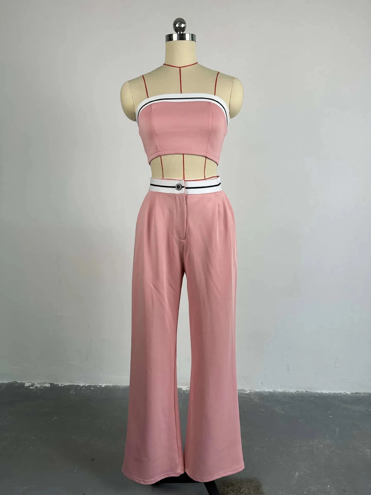 Pink strapless tube top with white-black striped trim and pink wide-leg pants with a white belt and black stripe.