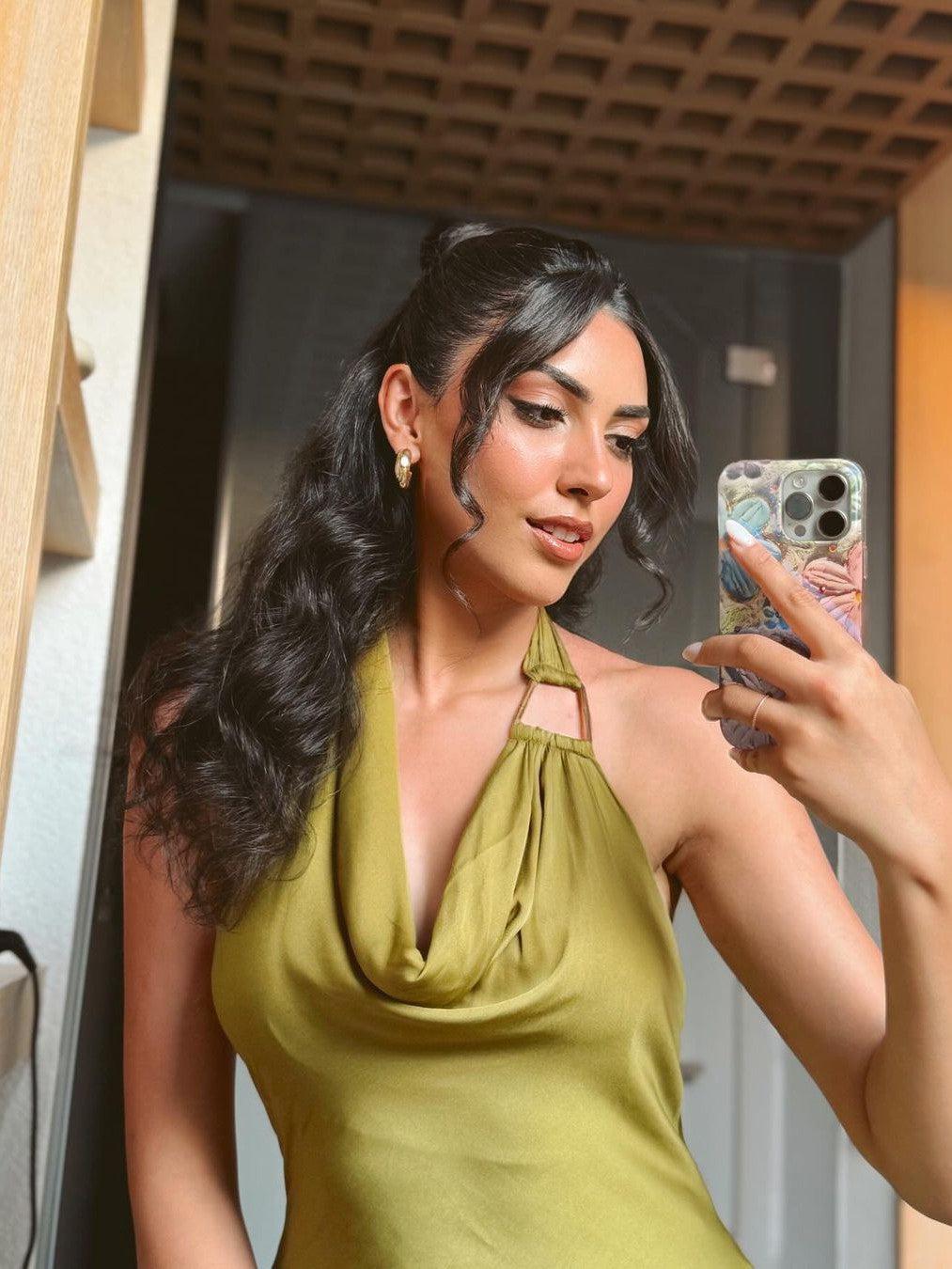 Olive green satin halter-neck dress with a draped cowl neckline, worn by a woman taking a mirror selfie.