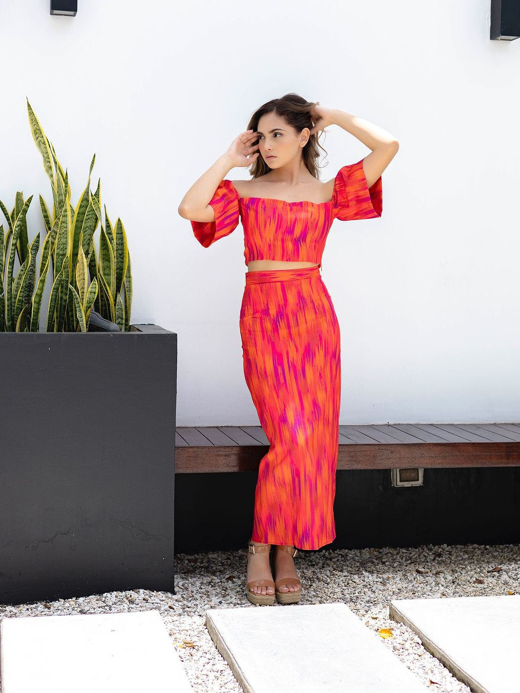 Bright pink-orange tie-dye off-shoulder puff-sleeve cami top with matching high-waisted maxi skirt, woman outdoors.