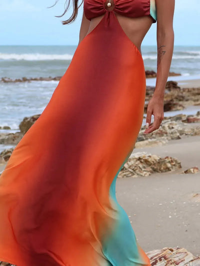 Gradient tie-dye cutout maxi dress in red, orange, and teal on a beach, halter top with ring accent.