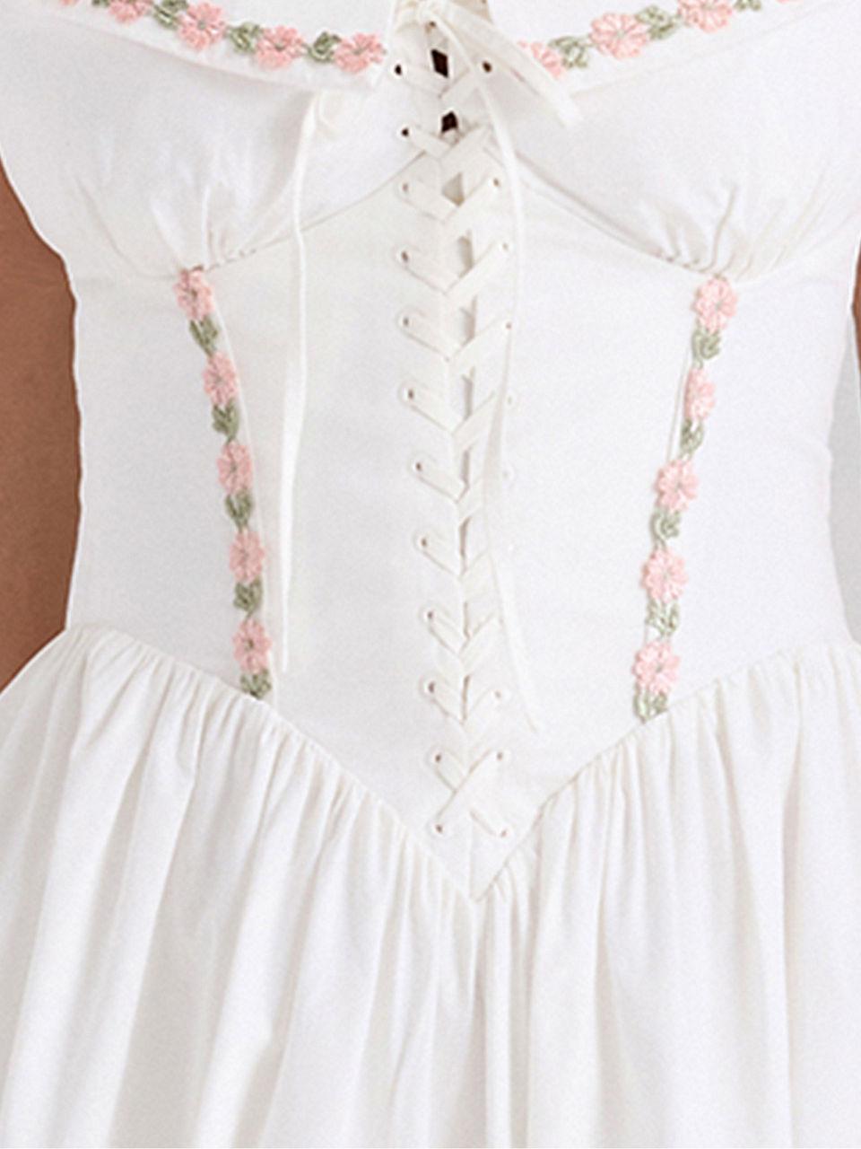 White corset halter dress with lace-up front and pink floral embroidery along vertical panels, gathered midi skirt.