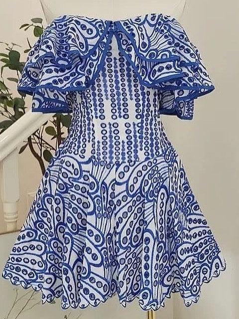 Blue and white off-shoulder cotton dress with puffed ruffle sleeves and intricate paisley embroidery, flared skirt.