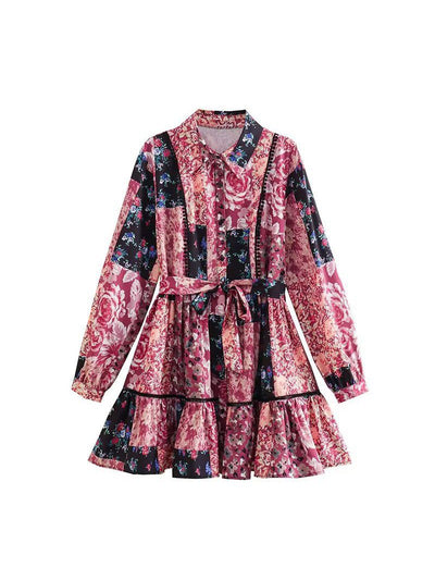 Patchwork floral print A-line dress with long sleeves, collared neck, waist tie, and tiered ruffled hem in pinks and blacks.