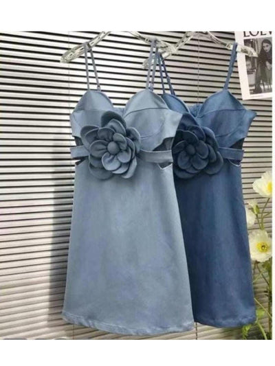Two satin spaghetti-strap dresses in light blue and navy, each with a large layered fabric flower at the waist.