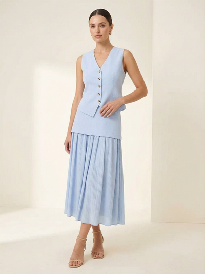 Light blue knitted vest with V-neck and gold buttons, paired with a pleated high-waist midi skirt and nude strappy heels.