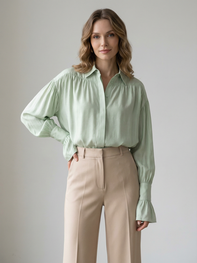 Model wearing a mint green oversized shirt with ruffled cuffs, paired with beige wide-leg trousers.