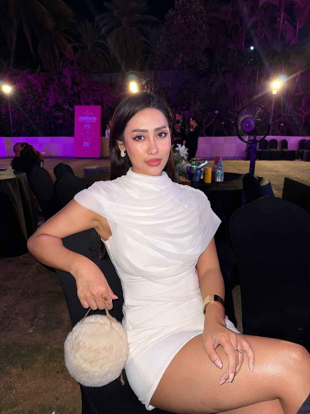 Asymmetric drape-shoulder white bodycon mini dress worn by a woman at an event