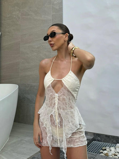 Cream sheer lace halter beach cover-up with floral pattern, front tie, and layered mini skirt.