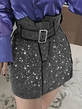 Black rhinestone mini skirt with dense silver studs, high waist, silver belt buckle, worn with a purple satin blouse.