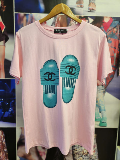 Light pink cotton-lycra T-shirt on a wooden hanger featuring teal slide graphics with Chanel logos.