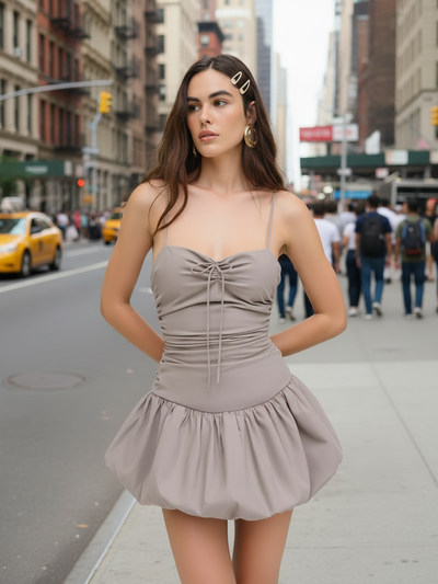 Spaghetti-strap ruched bodice puff skirt dress in taupe on a city street model