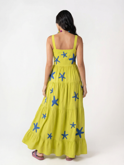 Back view of lime-yellow floor-length tiered maxi dress with blue starfish embroidery and thick straps.