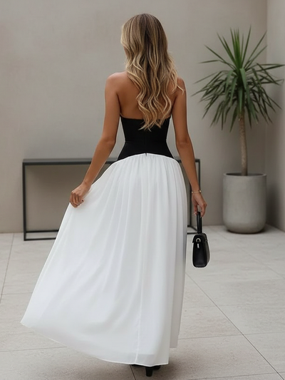 Back view of a woman in a two-tone halter corset maxi dress with a black bodice and white skirt, blonde hair.