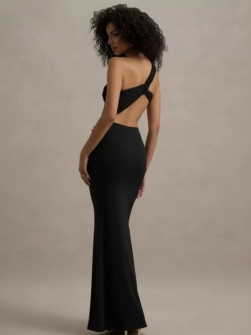 Back view of a model in a black one-shoulder cut-out bodycon maxi dress; single strap over left shoulder, back knot, floor-length.