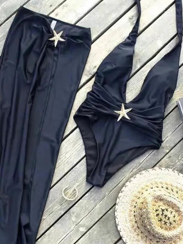 Navy blue halter-neck swimsuit with ruched wrap top and matching sarong skirt, starfish at waist, on a wooden deck.