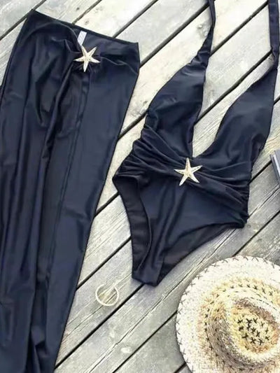 Navy blue halter-neck swimsuit with ruched wrap top and matching sarong skirt, starfish at waist, on a wooden deck.