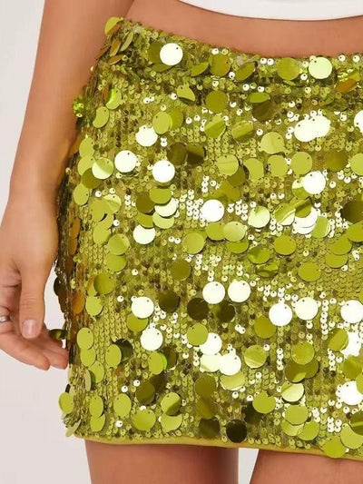 Lime-green coin-sequin mini skirt densely covered with shiny round discs; close-up of waist with a model's hand.