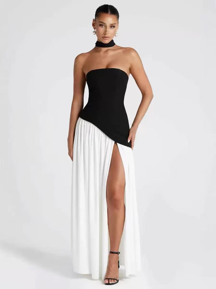Black strapless tube top with asymmetric hem over a white draped skirt with a high slit; black scarf and strappy heels.