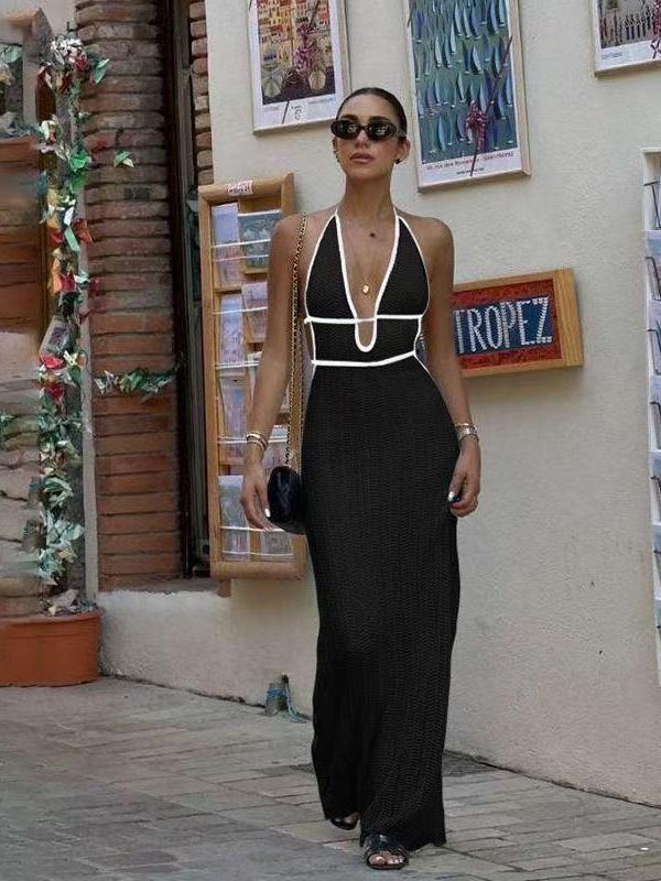 Black halterneck crochet backless maxi dress with white trim and waist cutouts, worn by a woman outdoors with sunglasses.
