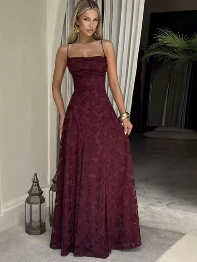Model wearing burgundy floral lace applique maxi dress with thin straps and fitted bodice, full layered skirt.