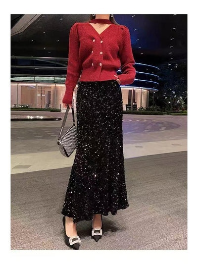Red V-neck cardigan with pearl buttons over a black sequin maxi skirt, paired with two-tone pumps and a checkered handbag.