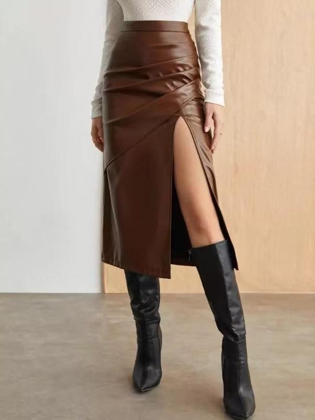 Brown faux-leather wrap midi skirt with diagonal draping and high slit, paired with white knit top and knee-high boots.