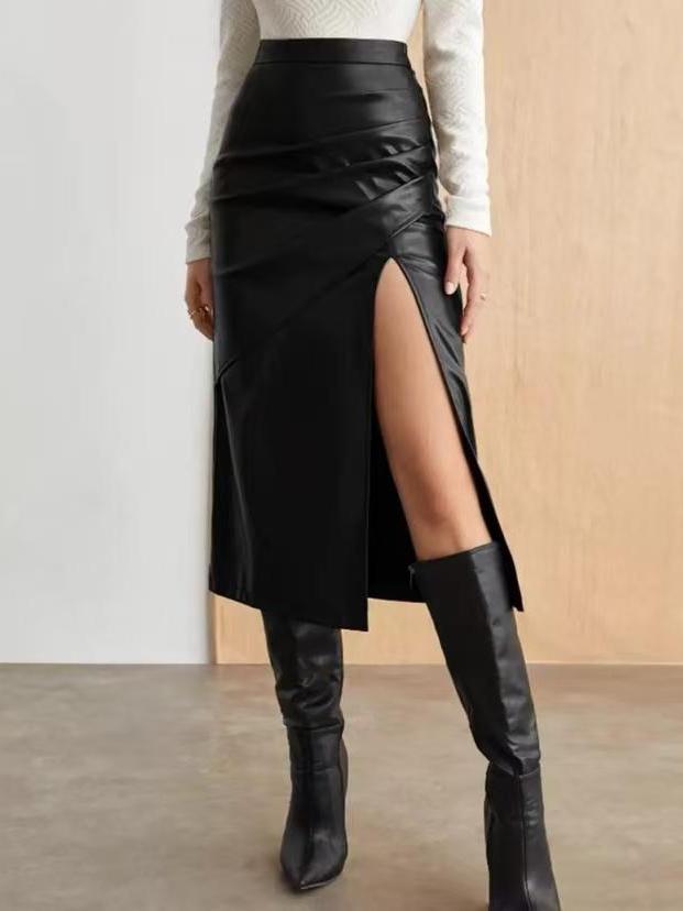 Black faux leather wrap midi skirt with a high slit and draped panels, paired with a white knit top and knee-high boots.