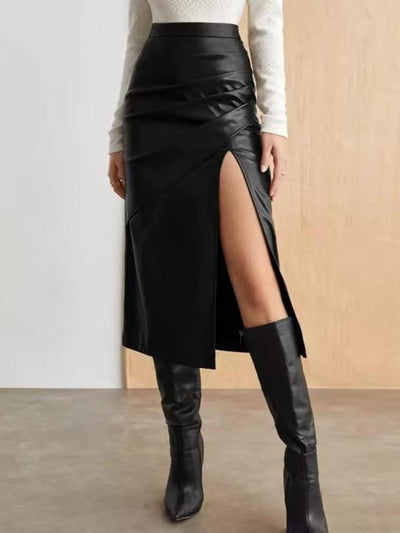 Black faux leather wrap midi skirt with a high slit and draped panels, paired with a white knit top and knee-high boots.