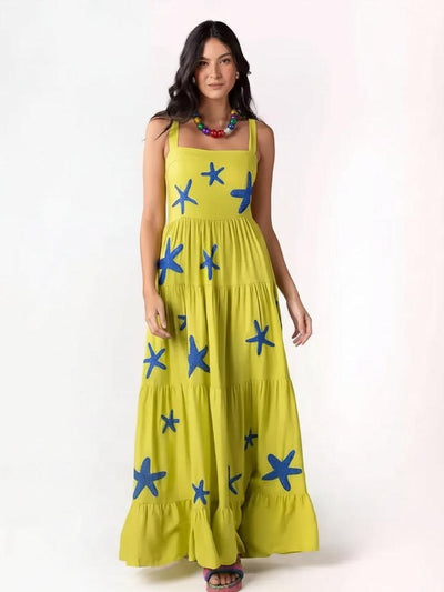 Model wearing lime-yellow, sleeveless square-neck tiered maxi dress with blue starfish embroidery and a ruffled hem.