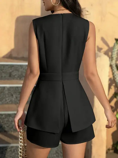 Back view of a model in a sleeveless black blazer and matching tailored shorts; center back vent and layered panels.