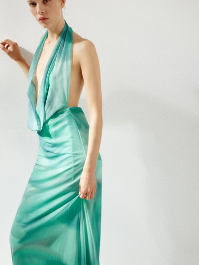 Ombre teal to turquoise satin halter-neck maxi dress with a draped cowl neckline on a model.