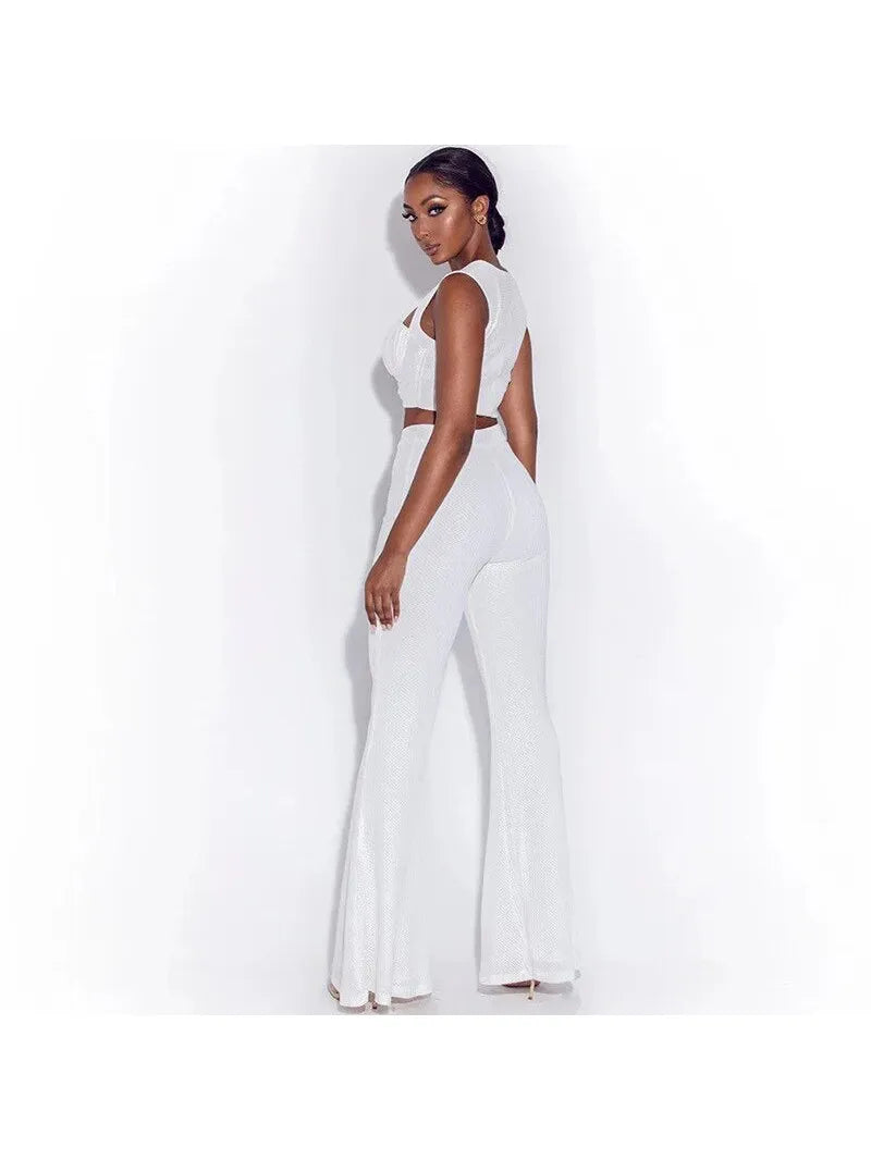 Profile view of a model in a white ruched crop top and matching high-waisted wide-leg pants, textured fabric.