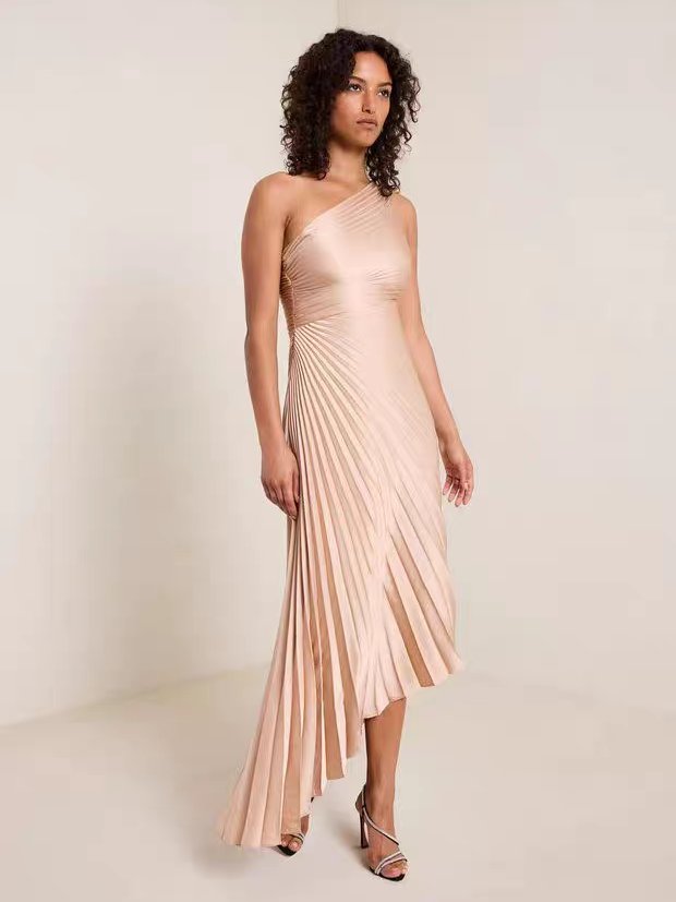 One-shoulder sun-pleated brown satin dress with flowing asymmetrical hem.