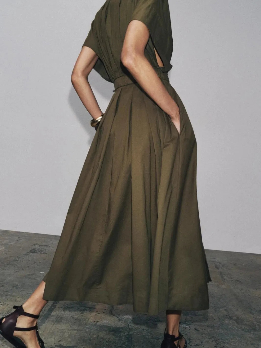 Olive green maxi dress with drawstring waist, draped short sleeves, full pleated skirt, and side pockets.