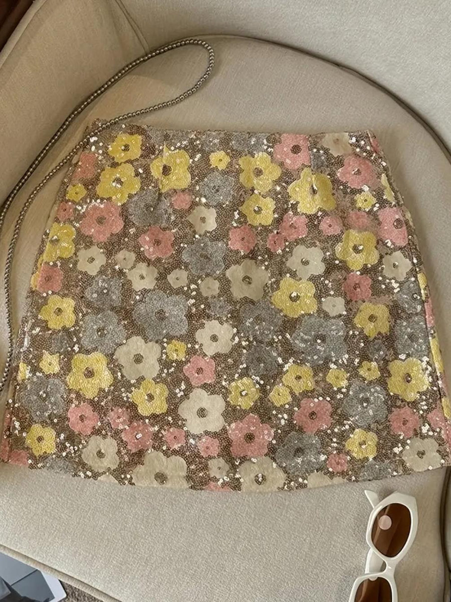 Pastel flower-patterned sequined mini skirt laid on a light beige couch.