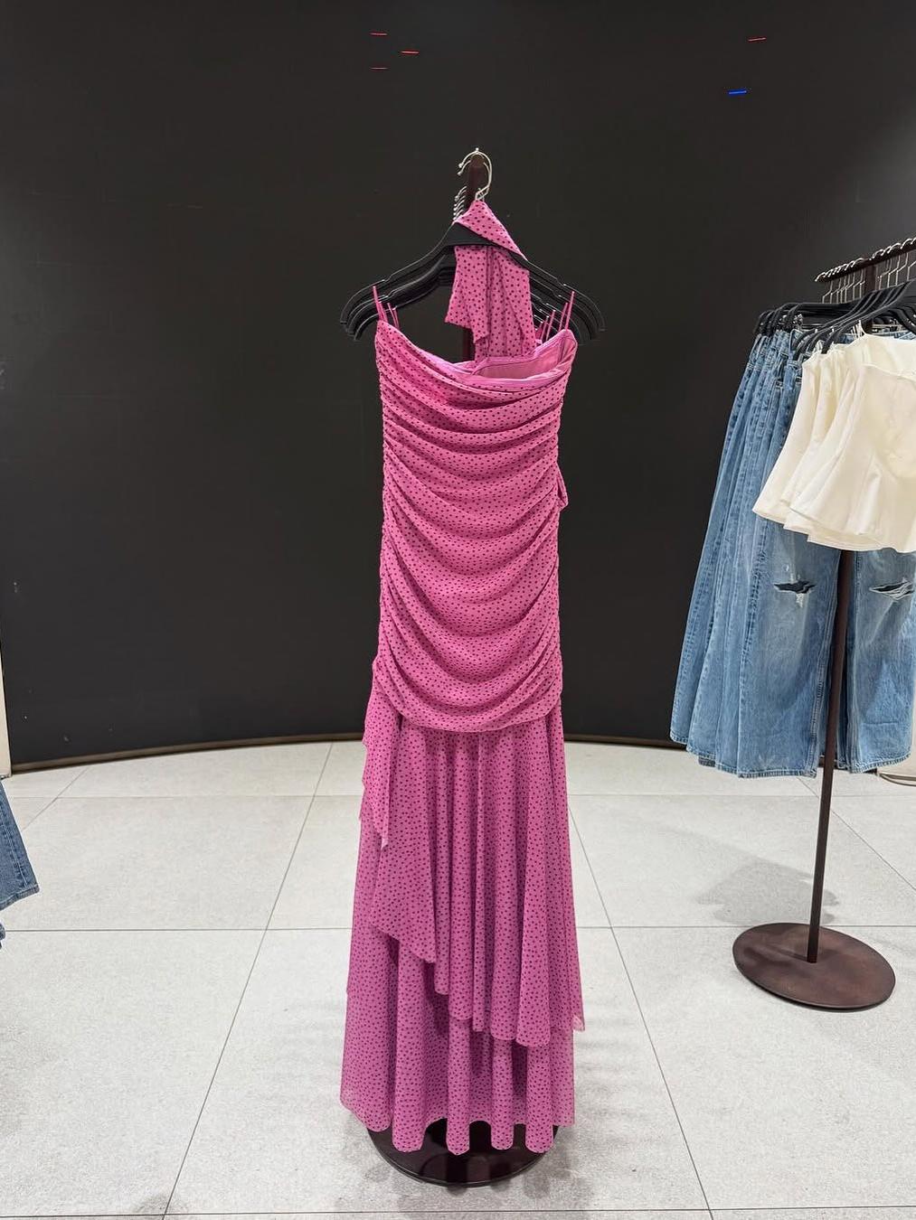 Pink polka-dot asymmetric ruffle dress with a draped bodice, floor-length skirt, side slit, and a matching scarf.