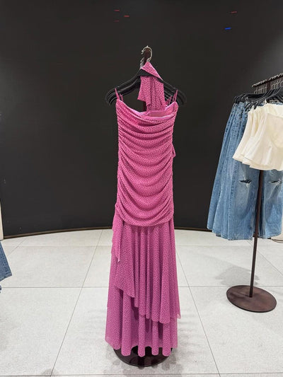 Pink polka-dot asymmetric ruffle dress with a draped bodice, floor-length skirt, side slit, and a matching scarf.