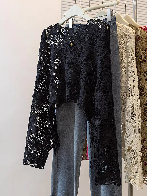 Black crochet top with butterfly hollow lace, long sleeves, cropped hem, on a hanger with blue jeans underneath.