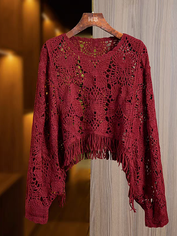 Burgundy crochet top with butterfly hollow lace, long sleeves, fringe tassel hem, on a wooden hanger.