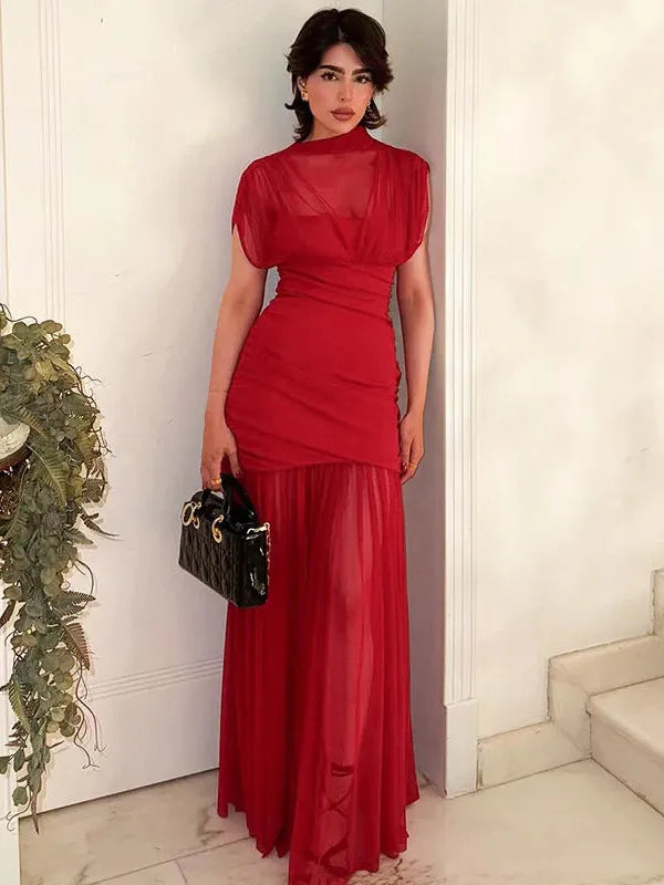 Red sheer mesh ruched pleated maxi dress with high neck and short sleeves; layered sheer skirt, model holding a black handbag.