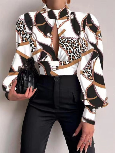 White satin crop top with leopard and chain print, keyhole neckline, sleeves, black pants, quilted clutch.
