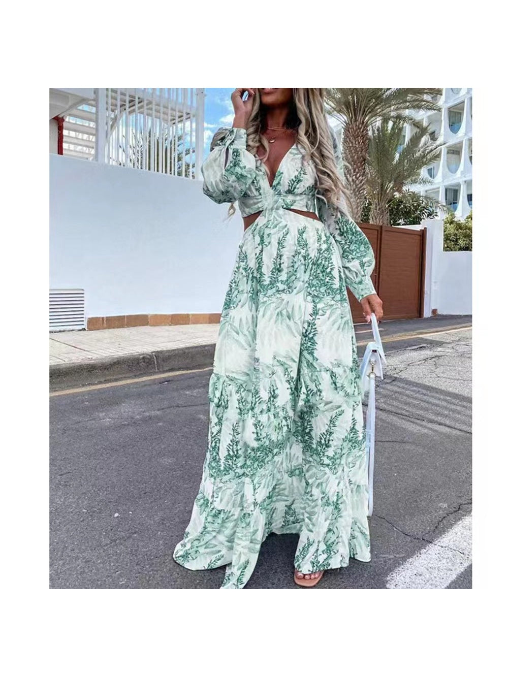 Woman in mint-green fern-print cutout-waist maxi dress with long puff sleeves and V-neck, holding a white handbag.